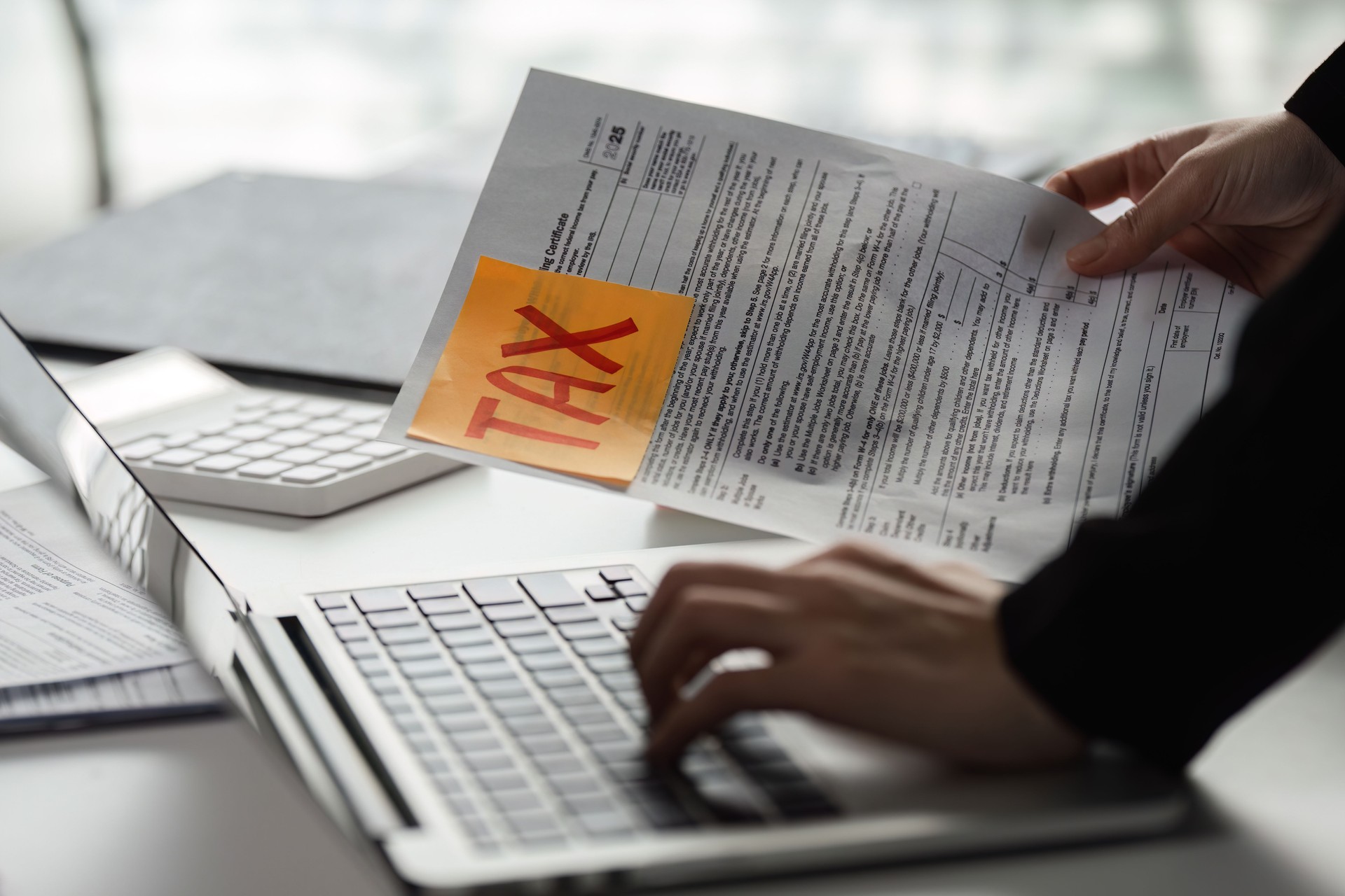 Individual preparing tax documents on laptop, emphasizing the importance of accurate filing